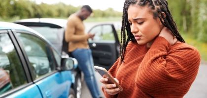Woman holding her neck and looking at her phone after a domestic violence incident